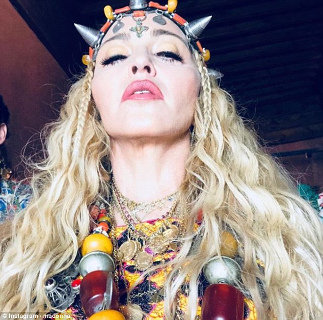 All hail: Also visible was a bejewelled orange and silver headband-come-crown on her head, which a day earlier, Madonna had unveiled in a series of sultry selfies
